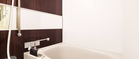 Une salle de bain avec une baignoire, une douchette et un miroir.