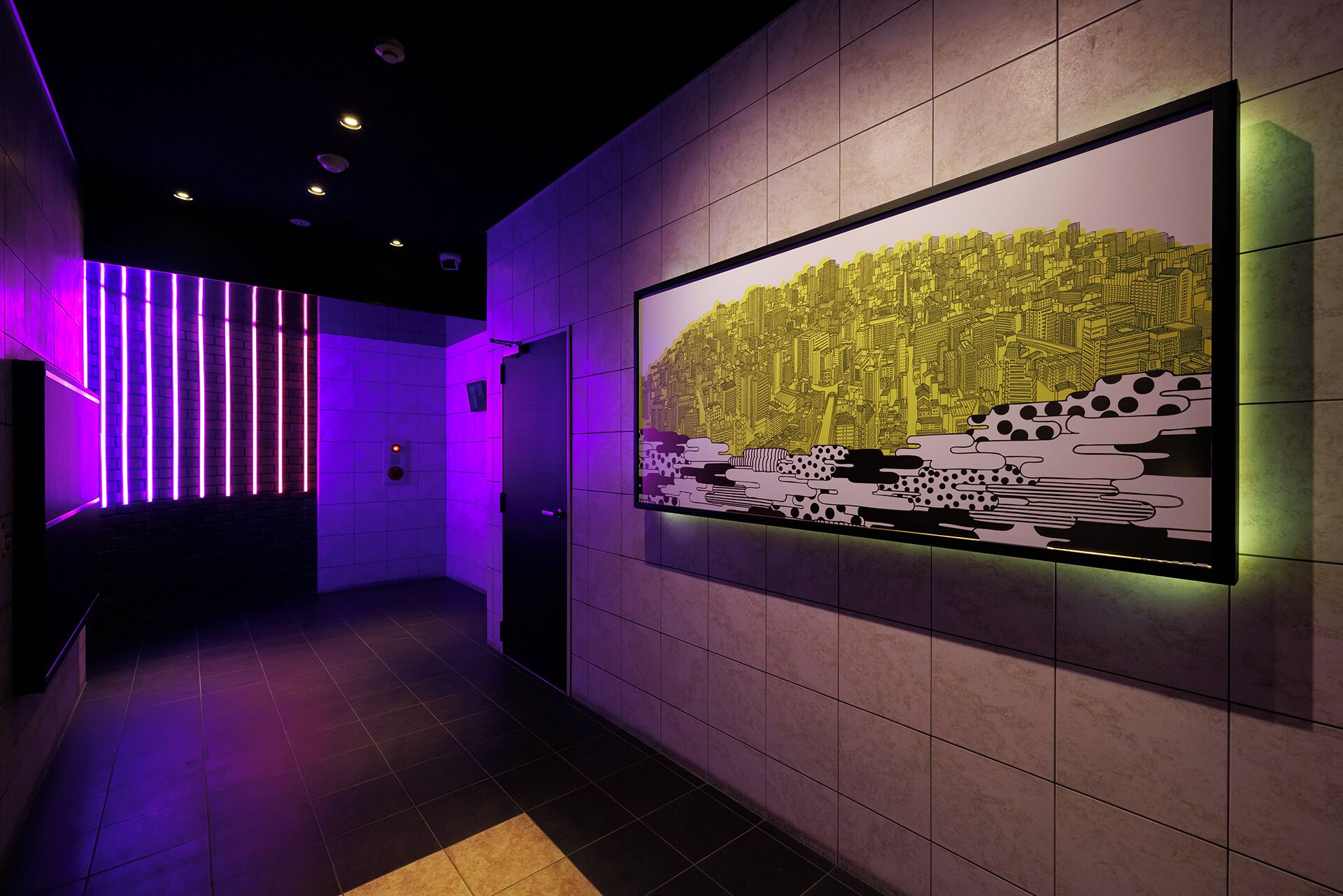 A hallway with a modern design, featuring a wall-mounted artwork of a cityscape and a door with a light switch.
