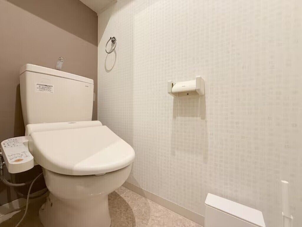 Een badkamer met een toilet, een hygiëneschuimer en een papieren handdoekdispenser.