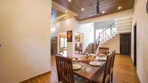 Comedor con mesa de madera dispuesta para seis personas, sillas y una escalera que sube a otro nivel.