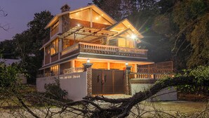 Una casa de varios pisos con balcón, entrada protegida por un portón y fachada bien iluminada.