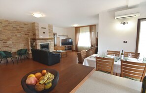 A living room with a fireplace, a television, a dining area with a table and chairs, and a fruit bowl. - Flat with shared pool in Fiorini (Fiorini)