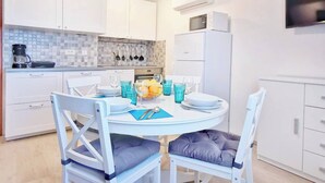 Una cucina moderna con mobili bianchi, forno integrato e zona pranzo con tavolo e sedie rotonde.