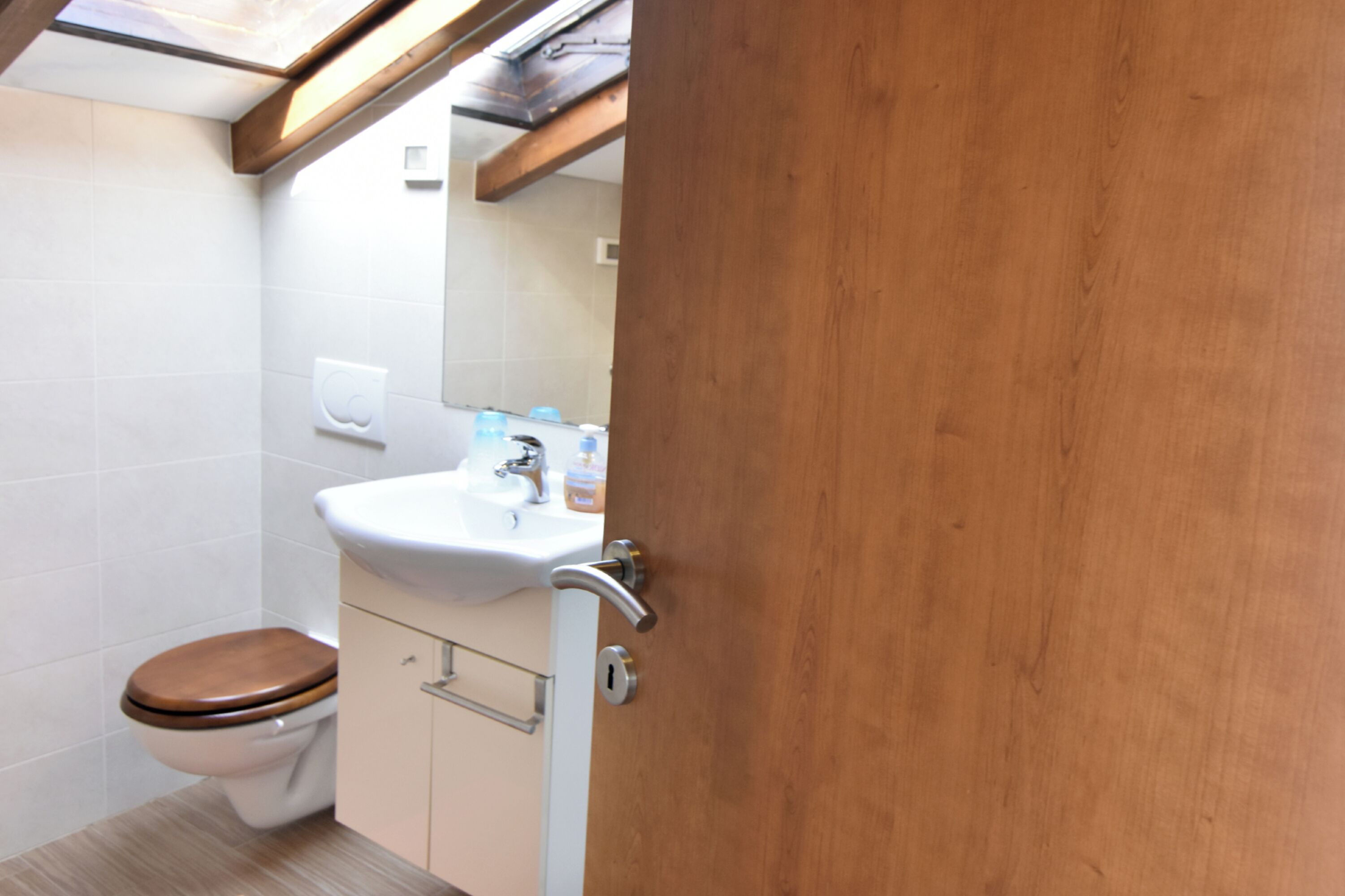 A bathroom with a toilet, sink, and wooden door.