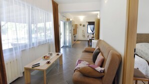 A living room with a sofa, a coffee table, and a TV. There is a kitchen area in the background. - Apartment near Kanegra Beach (Crveni Vrh)