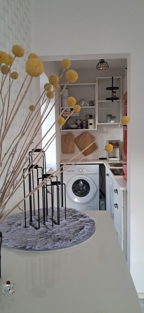 A laundry area with a washing machine, drying rack, and shelves with various items. - Apartment Retro, Geyersberg Sauna& Pool (Freyung)