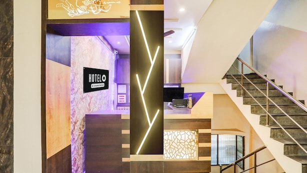 A hotel reception area with a modern design, including a reception desk, a staircase, and a sign indicating the hotel's name. - Premium Sanjeevi Residency (Rajahmundry)