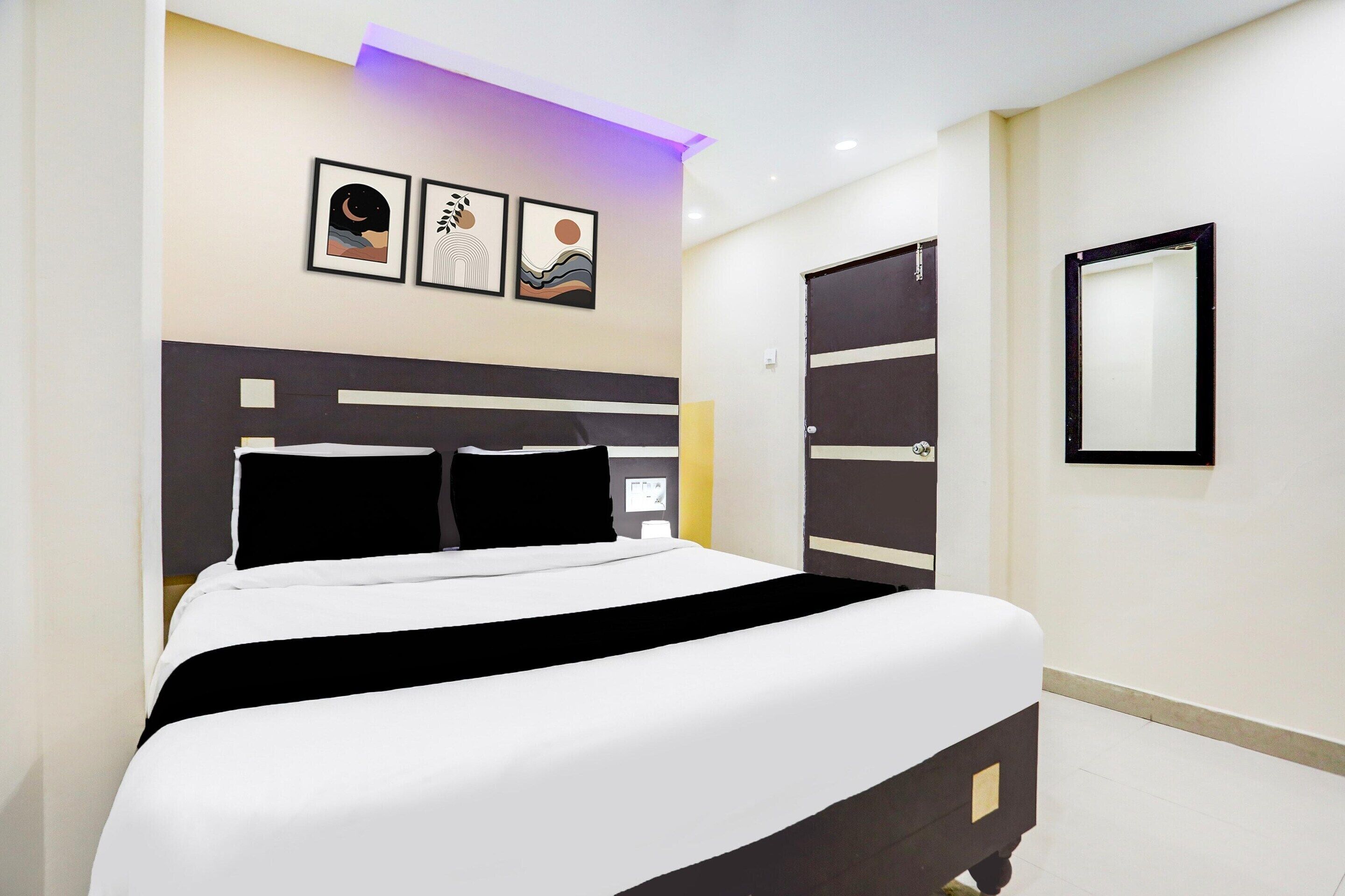 Ein Hotelzimmer mit einem Bett, einem Nachttisch, einem an der Wand montierten Fernseher und einer Tür mit Griff.