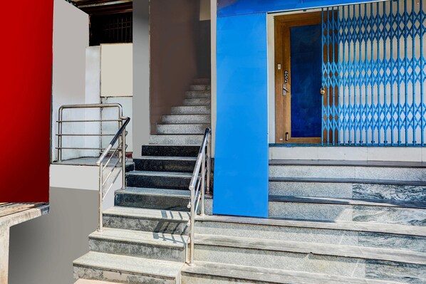 Una escalera que lleva a la entrada de un edificio, con barandilla de metal y puerta azul.