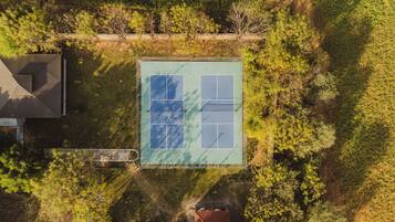 An aerial view of a tennis court surrounded by trees and a building.