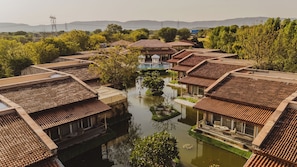 A traditional courtyard with tiled roofs, a central water feature, and surrounding greenery. - Brij Bageecha Kukas (Jamwa Ramgarh)