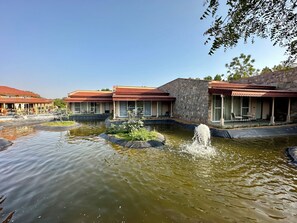 Un hotel con varias construcciones, un estanque con fuente y zonas de estar al aire libre.