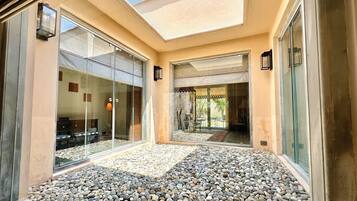 A modern building with glass doors, a patio area with pebbles, and a view of the interior.