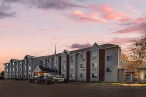 A multi-story hotel with a parking lot, featuring a modern architectural design with a mix of brick and siding.
