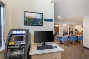 Un espacio interior con un cajero automático, una computadora y un cartel que indica un centro de negocios.