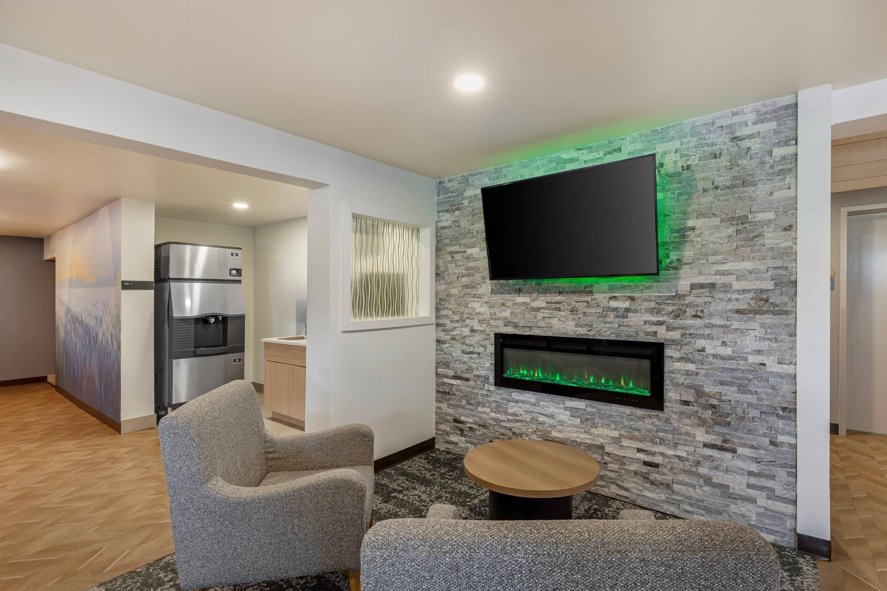 Una sala de estar moderna con un televisor de pantalla plana, una chimenea empotrada y una zona de cocina con refrigerador.
