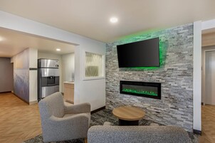Una sala de estar moderna con un televisor de pantalla plana, una chimenea empotrada y una zona de cocina con refrigerador.