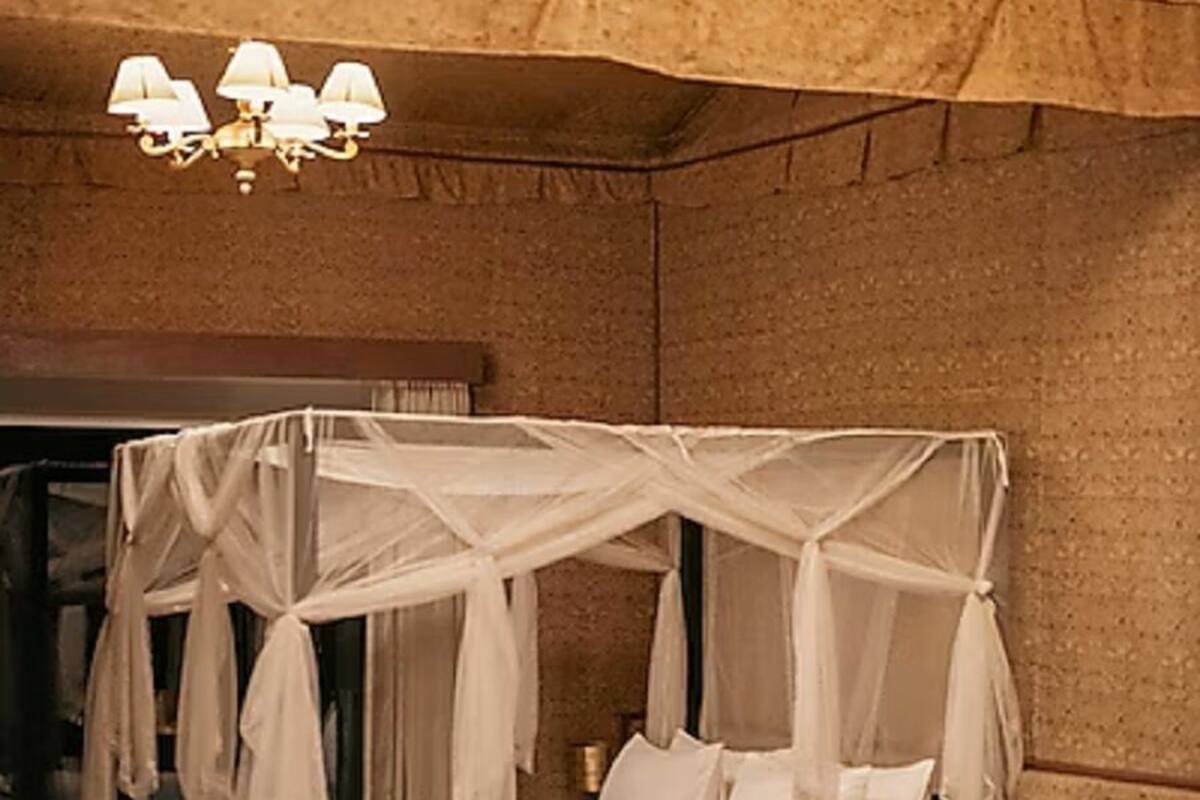 Una habitación con cama con dosel, candelabro, sofá y una pequeña mesa.