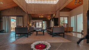 En rymlig entréhall med en central sittgrupp, en vacker blomsterdekoration och stora fönster som släpper in naturligt ljus.