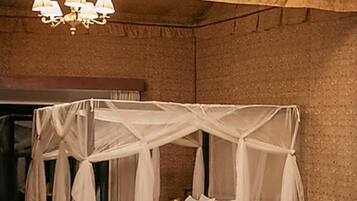 Una habitación con cama con dosel, candelabro, sofá y una pequeña mesa.