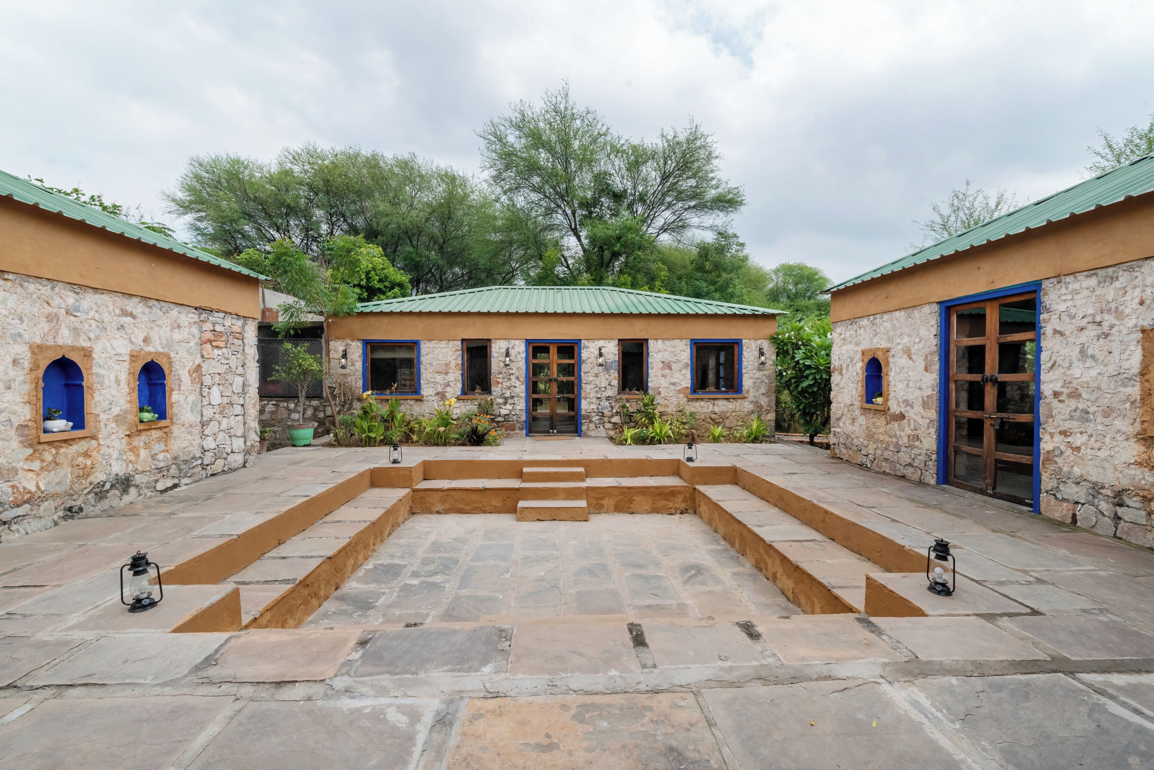 Un patio con edificios de piedra, un espacio central abierto y un techo verde.