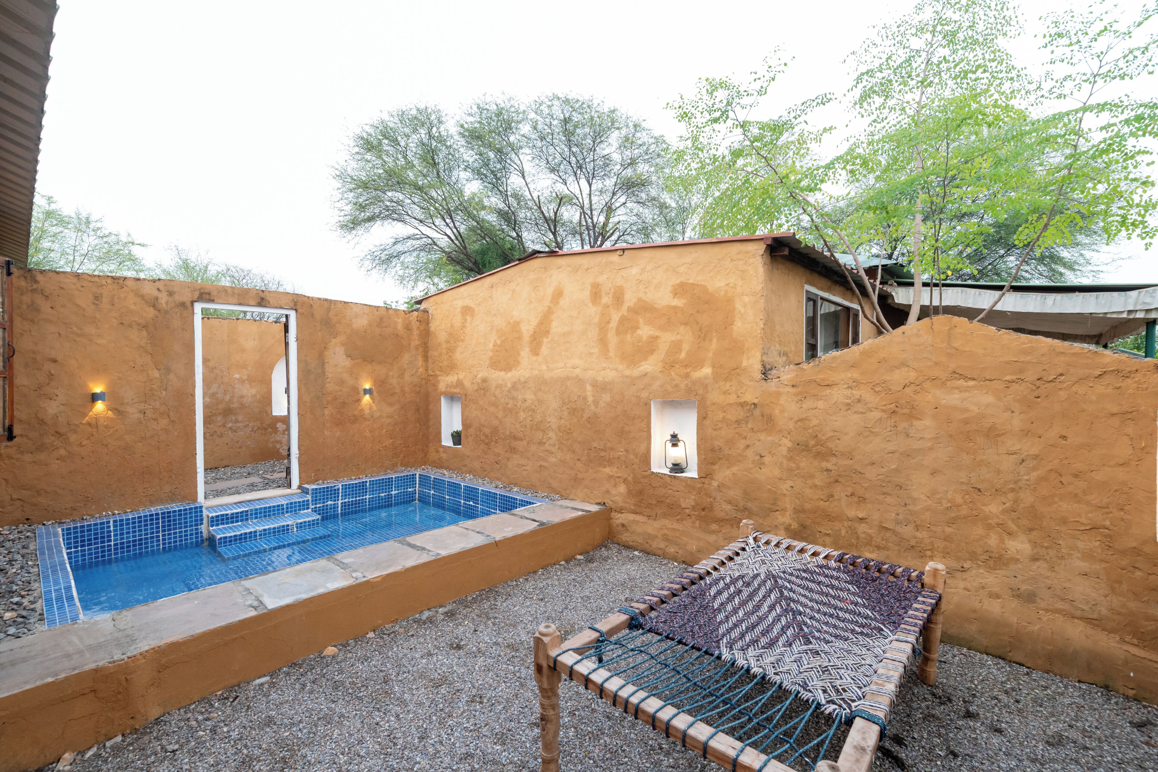 A pool with steps, a hammock, and a small structure with lights.