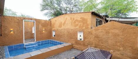 A pool with steps, a hammock, and a small structure with lights.