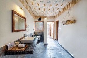 A bathroom with a large mirror, a sink, a bathtub, and a towel rack. - Bagh Serai by Alaya Stays (Sawai Madhopur)