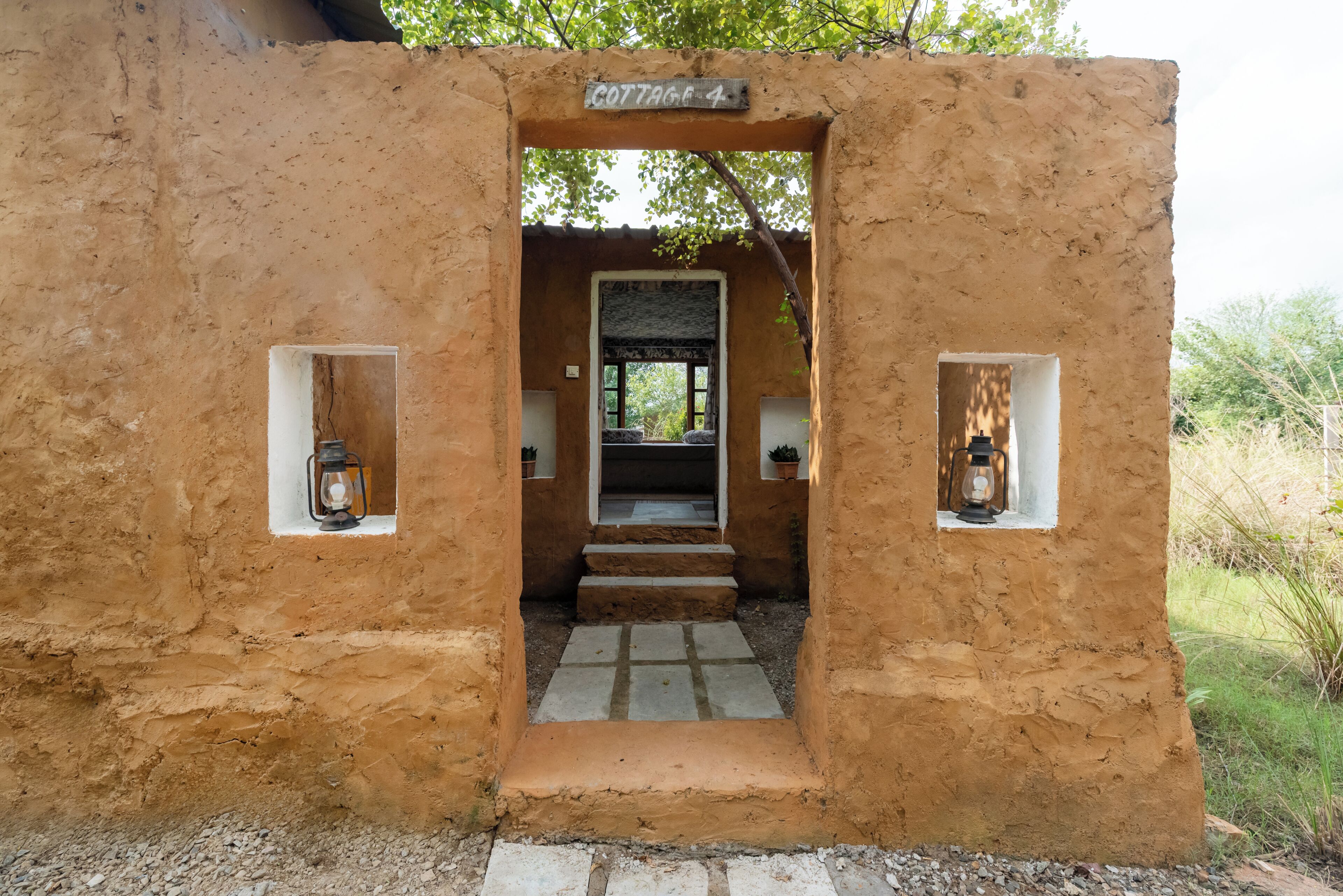 A rustic, mud-brick cottage entrance with a sign reading 'COTTAGE 4.'
