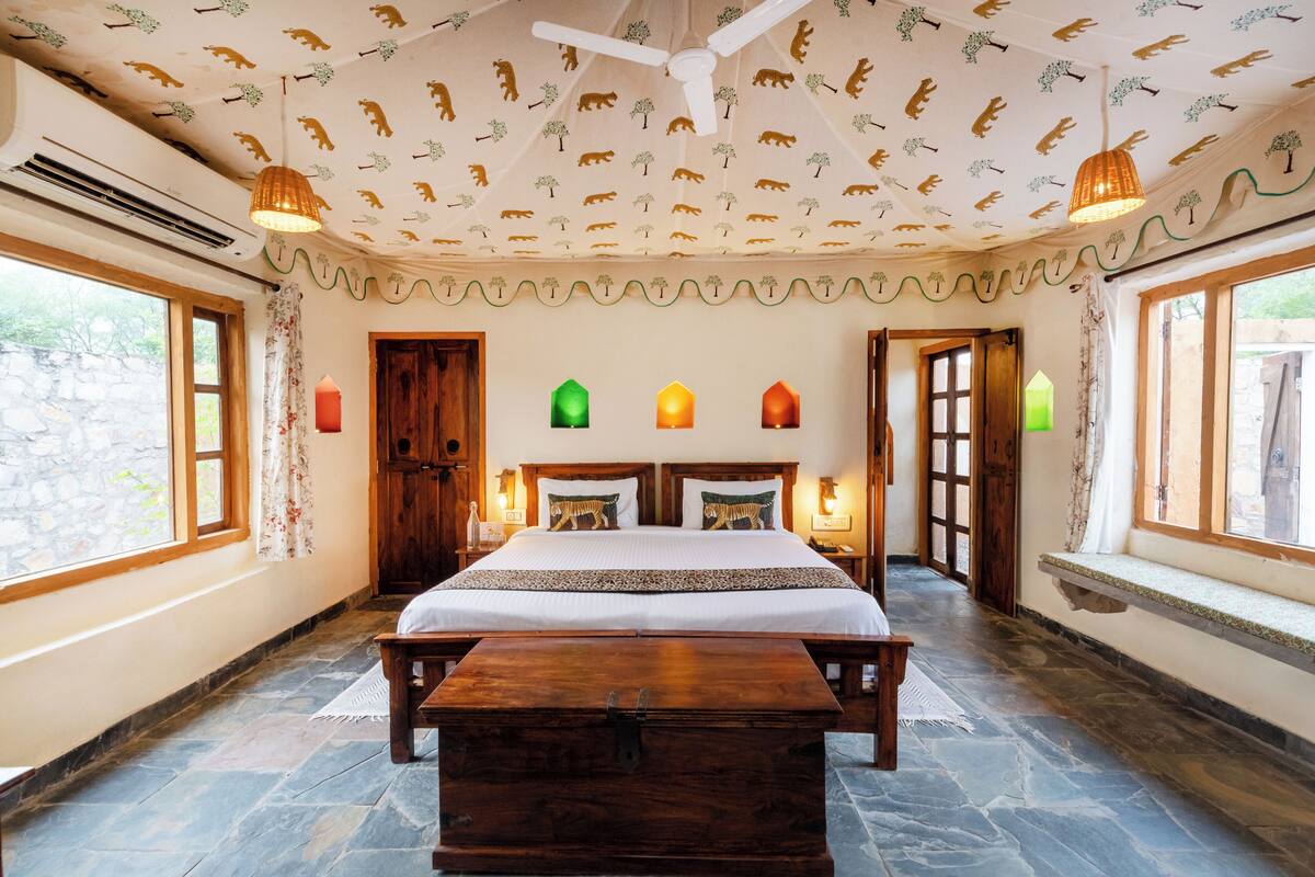 Un dormitorio con una cama grande, un cofre de madera y un techo decorado con motivos de animales.