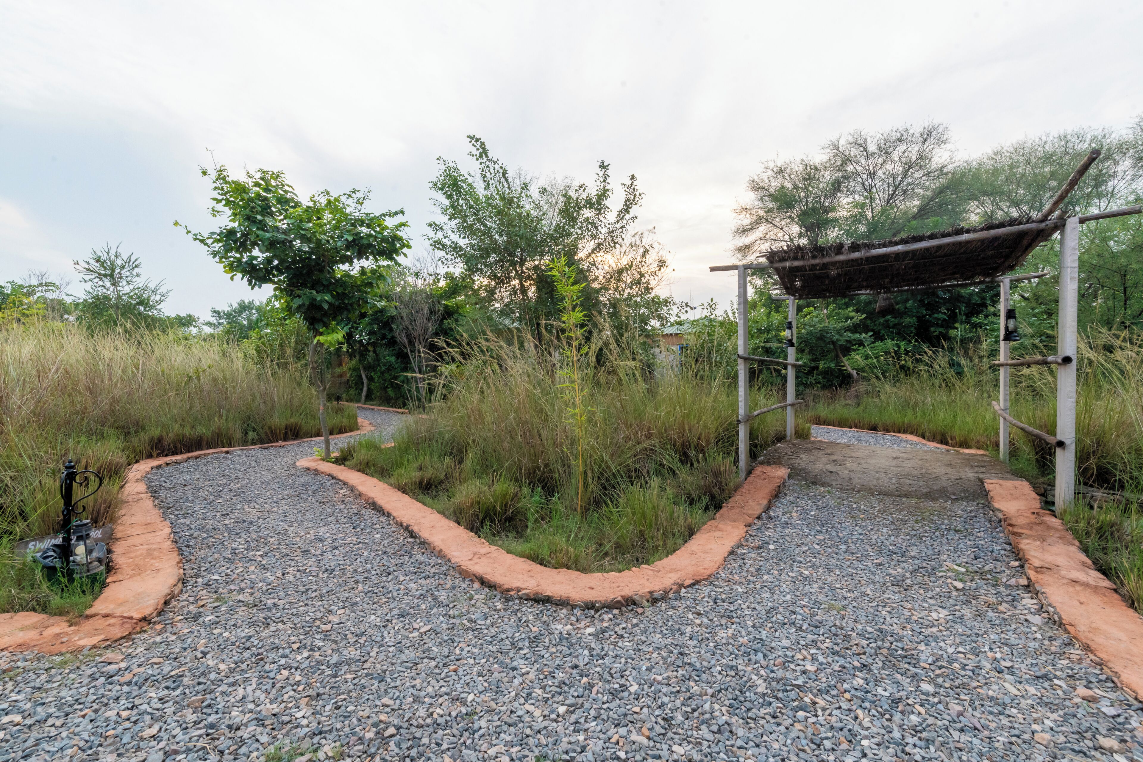 A gravel pathway leading to a covered structure amidst greenery.