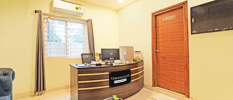 A reception desk with a sign reading 'Townhouse Company Service,' a computer, and a monitor.