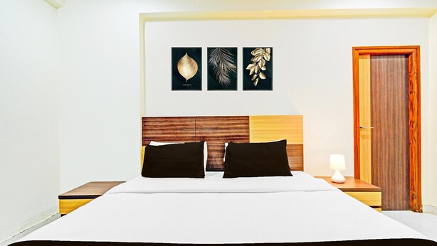 Habitación de hotel con cama, dos mesitas de noche, cabecero de madera y tres obras de arte colgadas en la pared.