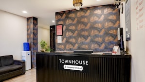 Un comptoir d’accueil portant l’inscription « TOWNHOUSE », agrémenté d’un panneau aux couleurs de l’entreprise, une fontaine à eau, une chaise bleue et un mur décoré de motifs.