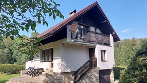 Une maison à deux étages dotée d’un balcon, d’un escalier en pierre et d’une antenne parabolique.