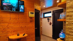 Un intérieur en bois avec un téléviseur diffusant des vidéoclips, un thermostat et une sphère de verre décorative.