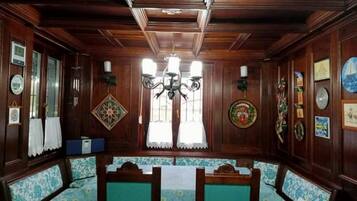 A room with wooden paneling, a chandelier, a bench with floral upholstery, and wall-mounted decorations.