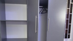 Ein grauer Kleiderschrank mit mehreren Einlegeböden, Schubladen und einer Schiebetür.