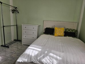 A bedroom with a bed, a white dresser, and a metal rack. - Modern 2-bedroom Apartment near Roseau (Roseau)