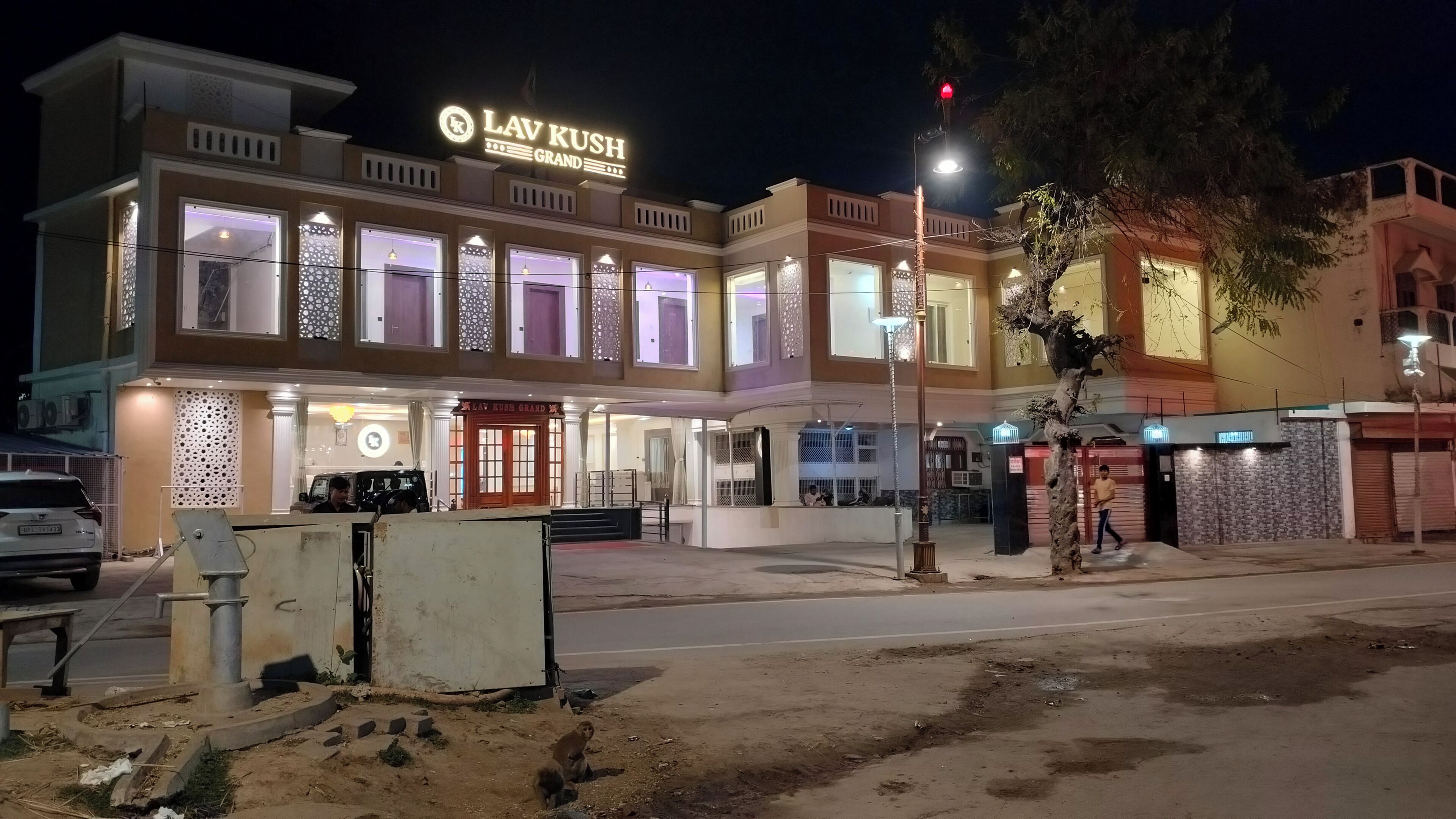 A hotel named 'Lav Kush Grand' with a modern facade, large windows, and a prominent entrance.