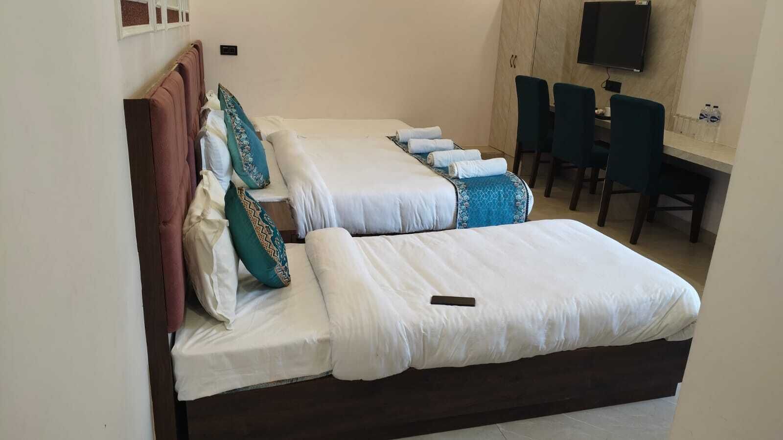 A hotel room with two beds, a desk, and a TV.