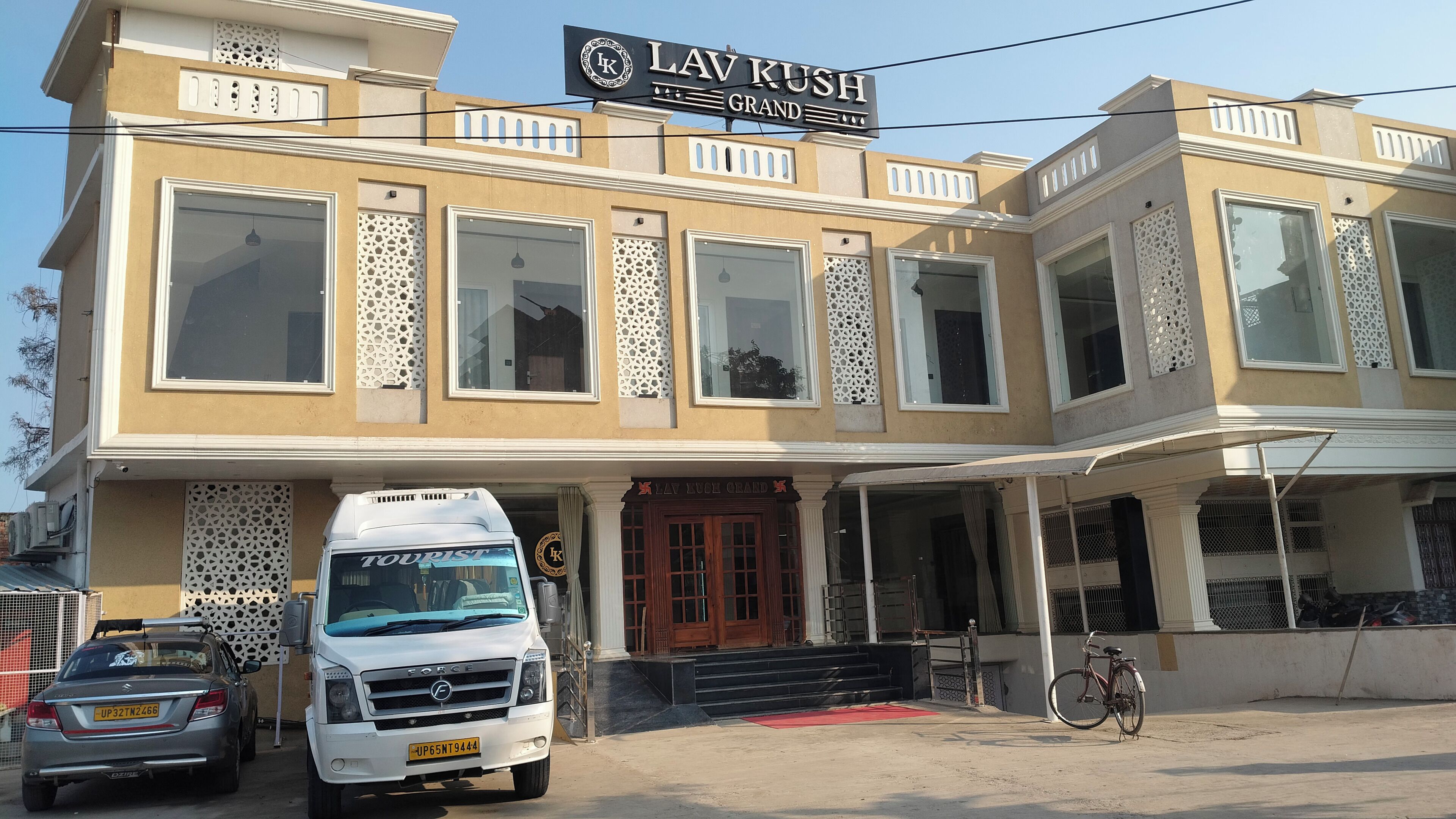 A building with a sign reading 'LAV KUSH GRAND' and a white van parked in front.