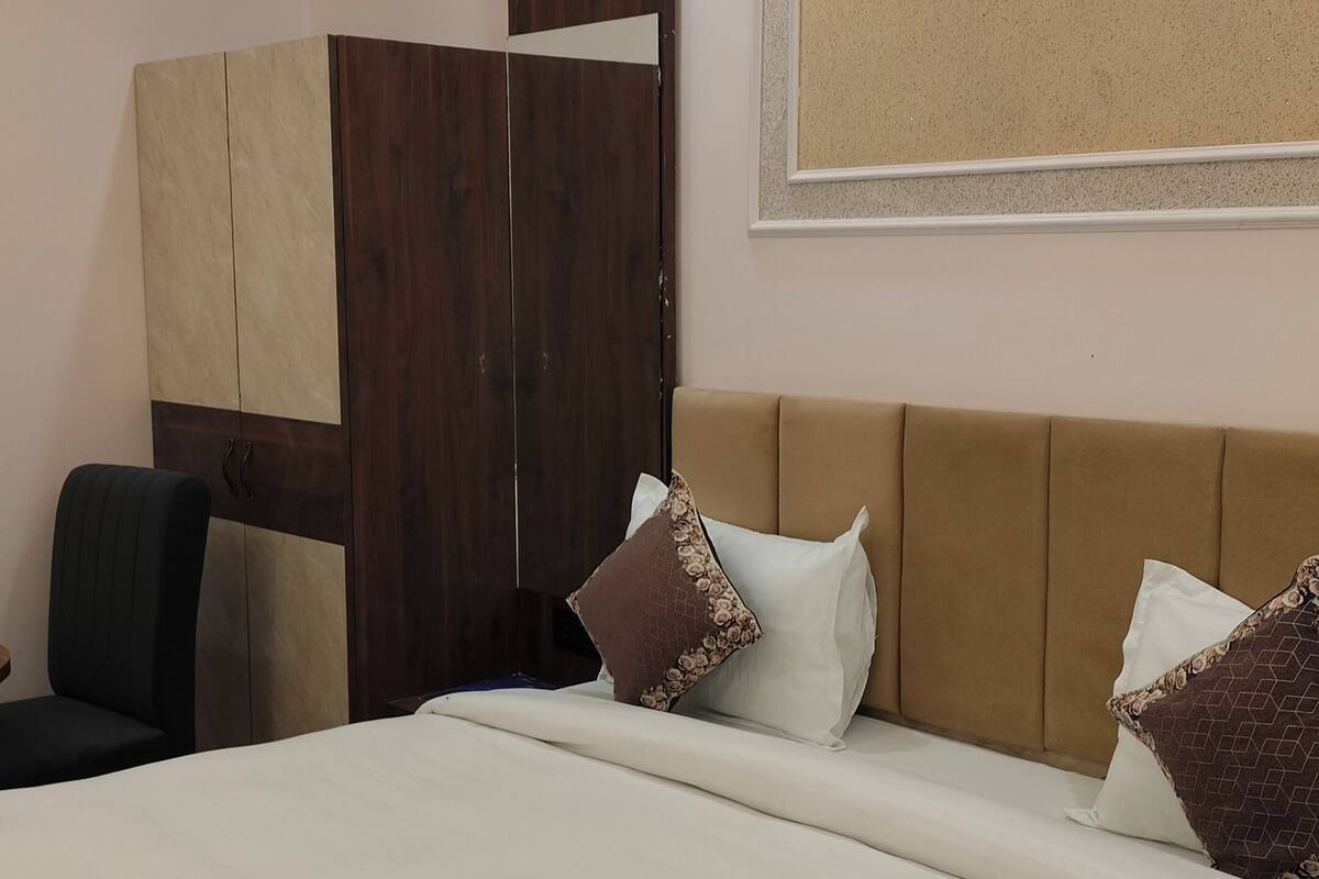 Een hotelkamer met een groot bed, een garderobe, een bureau en een kunstwerk aan de muur.