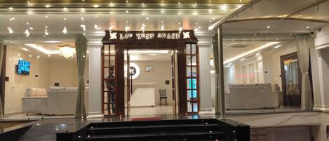 A hotel entrance with a reception desk, a staircase leading up, and a modern interior design.