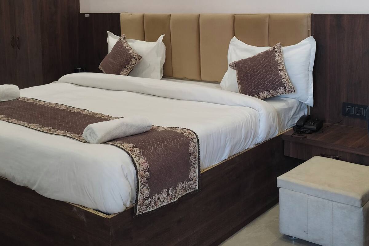 Een moderne slaapkamer met een groot bed, een nachtkastje en een klein krukje.