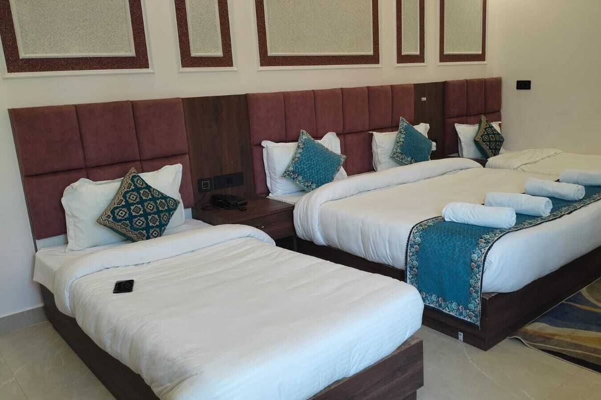 Een hotelkamer met twee bedden, elk met hoofdeinde, witte lakens en decoratieve kussens.