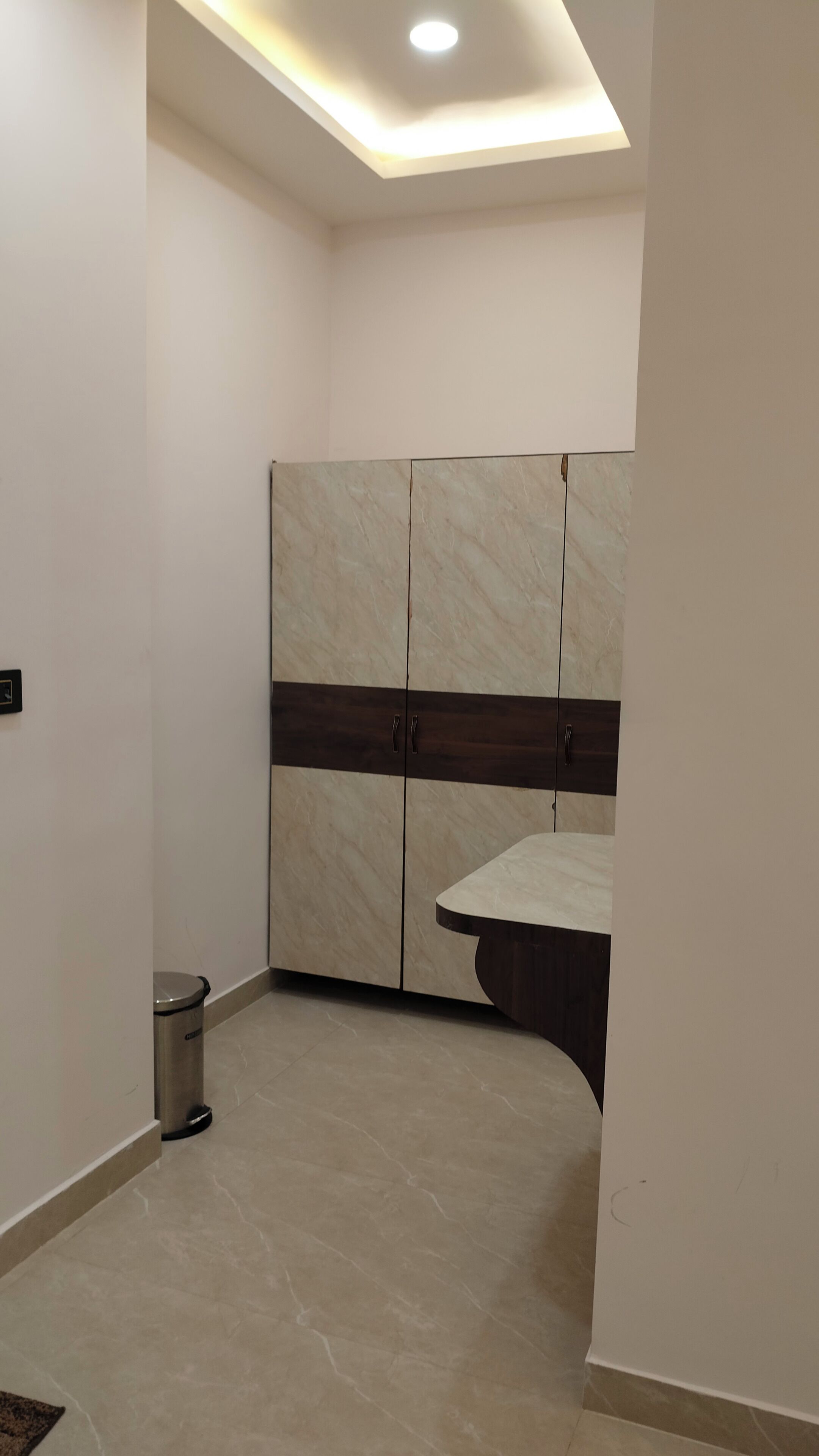 Une pièce comprenant une armoire, une poubelle et un luminaire encastré au plafond.