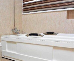 A white bathtub with a faucet and a control panel. - Efeane De-Comfy Apartments. (Magboro)