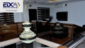A living room with a chandelier, a television, and a balcony with railings. - Efeane De-Comfy Apartments. (Magboro)