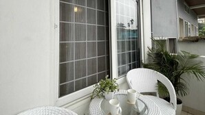 Un balcon avec deux chaises en osier blanc, une petite table et une plante en pot.